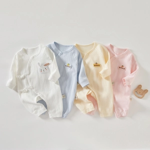Flat lay of ribbed cotton baby rompers in pastel colors with soft embroidery details
