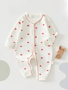 Détail d'une barboteuse en coton pour bébé avec motifs de cœurs rouges et boutons
