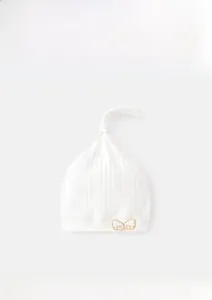 Detail of baby cotton cap with ribbed texture and gold wing embroidery pattern