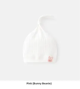 Detailed macro view of white ribbed cotton baby beanie with pink rabbit embroidery patch