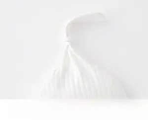 Detail of soft ribbed cotton baby hat featuring a cute adjustable top knot design
