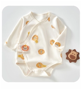 Detail of infant organic cotton wrap romper with cartoon mushroom print and lion patch