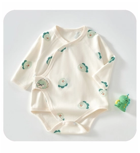 Detail of baby cotton bodysuit featuring green cartoon dinosaur prints and snap buttons