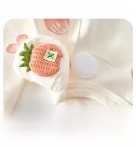 Detail of baby bodysuit showing adjustable velcro strap and cute carrot embroidery