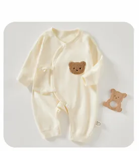Detail of newborn cotton bodysuit featuring 3D plush bear embroidery and side tie closure