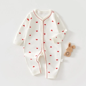 Détail d'un barboteuse bébé en coton avec motifs cœurs rouges et bordure ondulée