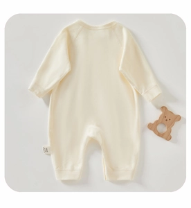 Macro detail of soft cotton baby romper with long sleeves and wooden bear teether