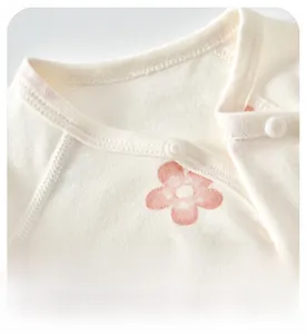 Detail of the soft cotton neckline with snap buttons and pink floral print for babies