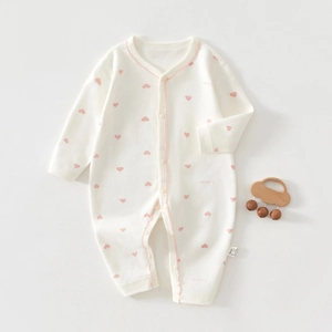 Détail d'une barboteuse en coton doux pour nouveau-né avec motifs cœurs roses et boutons