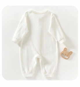 Detail view of cream-colored ribbed cotton baby romper with soft texture and wooden toy decor