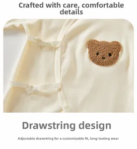 Detail of baby cotton bodysuit with adjustable side ties and brown bear embroidery