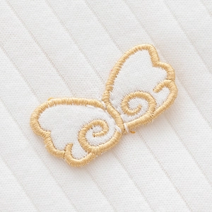 Newborn baby cotton hat with elegant golden embroidered angel wings on white fabric