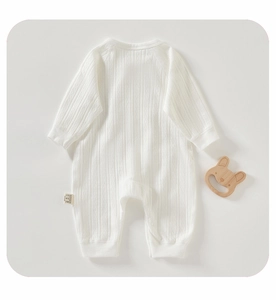 Close-up of white newborn ribbed cotton romper with textured jacquard and wooden bunny toy