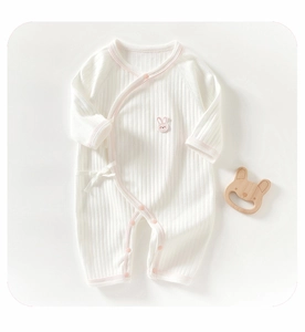 Close-up of white ribbed cotton baby romper with pink piping and bunny embroidery detail
