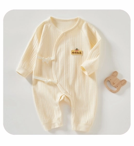 Close-up of ribbed cotton baby romper with persimmon embroidery and bow details