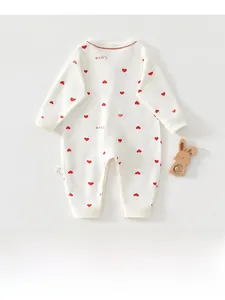 Détail d'un barboteuse bébé à manches longues avec imprimé cœur rouge et coton doux