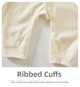 Detail of ribbed cuffs and resin snap buttons on cream cotton newborn baby bodysuit
