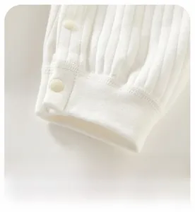 Detail of ribbed cotton baby romper cuffs with side resin snap buttons in beige color