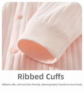 Vue détaillée des poignets en coton rose et d'un bouton en résine sur un vêtement bébé