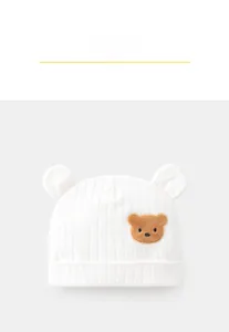 Dettaglio cappello bianco in cotone per neonato con orecchie 3D e ricamo orso marrone