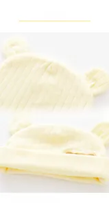 Dettaglio del cappellino in cotone neonato con orecchie 3D e polsini a costine gialli