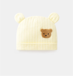 Dettaglio del cappellino giallo chiaro per neonato con patch a orso e maglia morbida