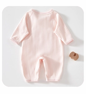 Flat lay of soft pink ribbed cotton baby romper with long sleeves and wooden elephant toy