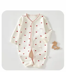 Détail d'une grenouillère bébé en coton blanc avec cœurs rouges et boutons-pression pratiques