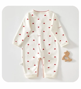 Détail d'un pyjama bébé en coton blanc avec imprimé cœurs et broderie Love rouge