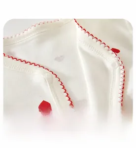 Détail d'un body bébé en coton blanc avec imprimé cœurs et boutons-pression sécurisés