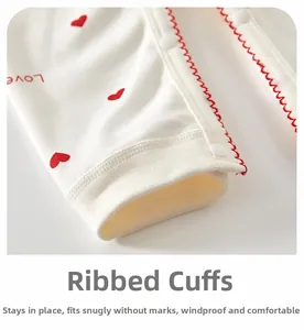 Détail des poignets côtelés avec motif de cœur rouge et boutons-pression sur le pyjama bébé