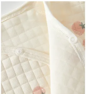 Detail of baby quilted cotton top with safe resin snap buttons and peach print