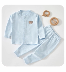 Detail of light blue cotton baby sleepwear set featuring a cute brown bear patch