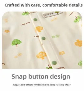 Detail of beige cotton baby onesie with tree patterns and green resin snap buttons