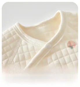 Close-up of the hemmed neckline and soft quilted fabric with peach patterns on baby top