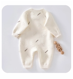Detail of soft cream baby romper featuring dog prints and ribbed cuffs in cotton
