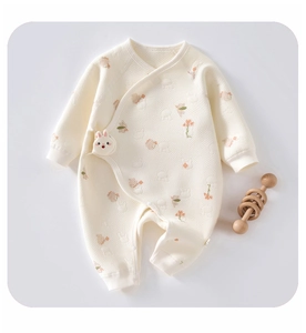 Detail of quilted newborn bodysuit with rabbit floral print and plush bunny accessory