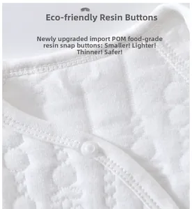Close-up of eco-friendly resin buttons on white waffle cotton baby jumpsuit fabric