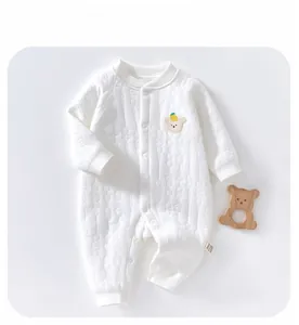 Detailed view of ivory quilted cotton baby romper with yellow bear embroidery and side label