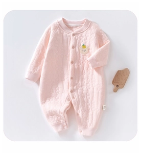 Detail of pink quilted baby romper featuring a 3D cartoon bear patch and soft cotton texture