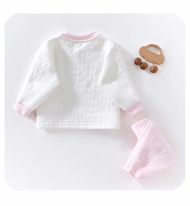 Close-up of quilted thermal baby set with white top, pink trim, and textured fabric