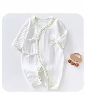Detail of baby cotton romper featuring green piping, rainbow patch, and ribbon ties