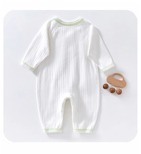 Close-up of white ribbed cotton baby bodysuit with green trim and soft fabric texture