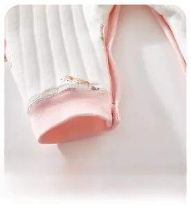 Détail macro des poignets élastiques roses sur une grenouillère en coton pour bébé