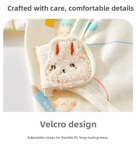 Détail d'un haut pour nouveau-né en coton avec fermeture velcro et petit lapin en peluche