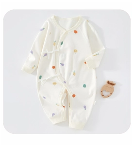 Detail view of newborn cotton romper featuring cartoon vegetable prints and ribbon ties