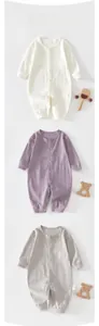 Detailed close-up of newborn cotton jumpsuits in white, lilac, and grey with snap buttons