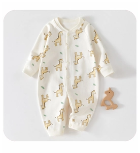 Detail of soft cotton baby romper with giraffe print and snap buttons on flat lay