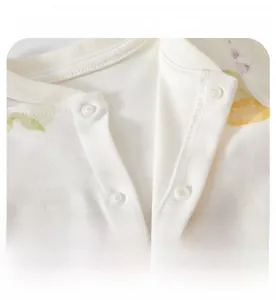 Detail of round neckline with white snap buttons on soft cotton baby romper
