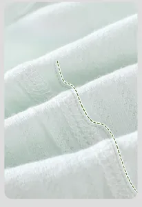 Détail de la couture plate sur un body pour bébé en coton doux de couleur vert clair